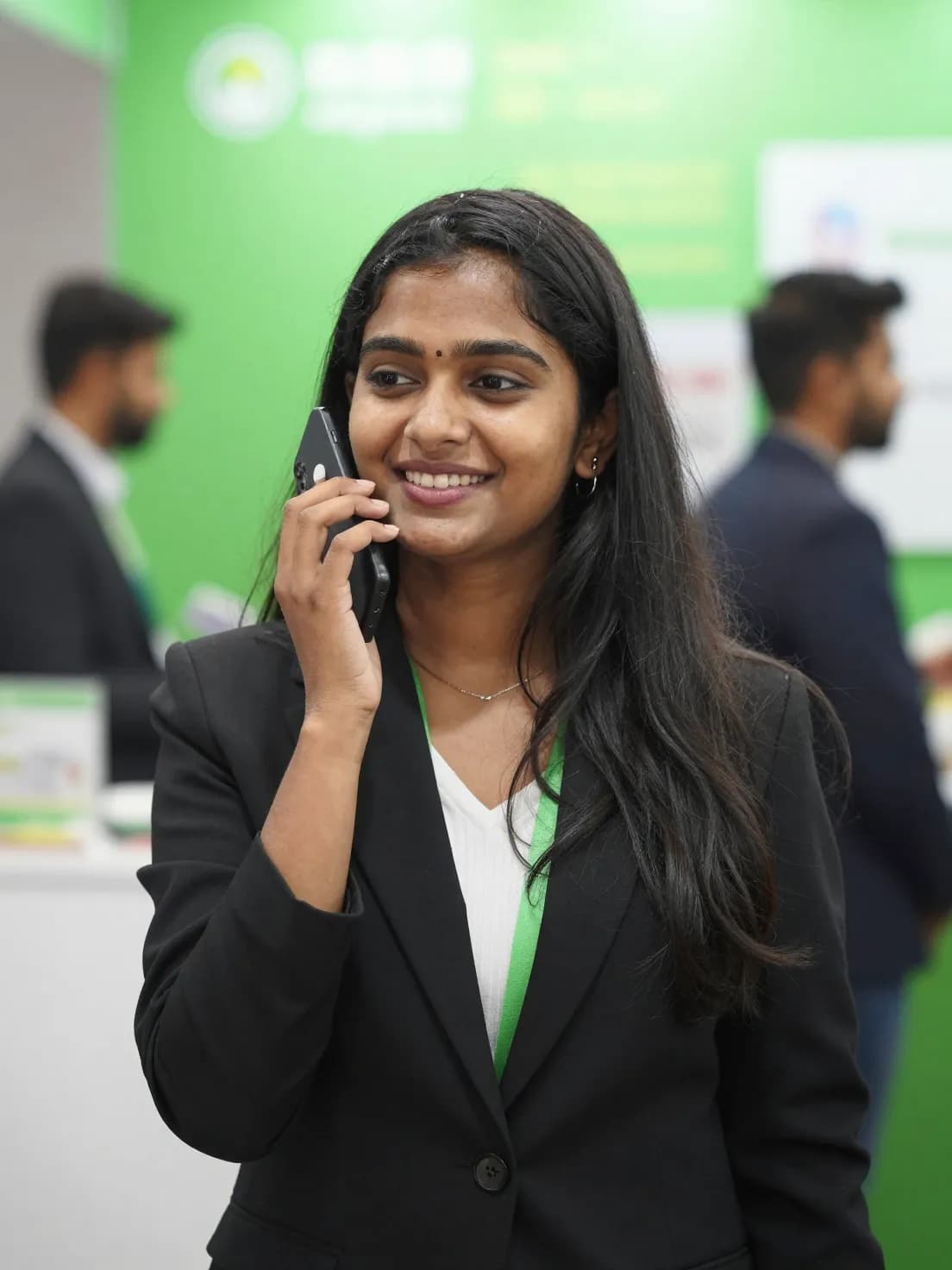 A saleswoman at an exhibition booth speaking a voice note into her phone